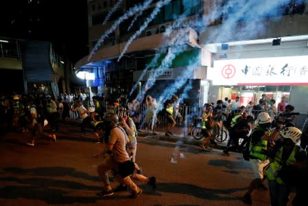 Protesters react to tear gas after a sit-in at Yuen Long to protest against violence that happened two months ago when white-shirted men wielding pipes and clubs wounded both anti-government protesters and passers-by, in Hong Kong