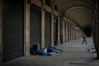 Homeless people sleep on a square where restaurants are closed due to sharpest resurgences of the new coronavirus in Barcelona, Spain, Monday, Oct. 19, 2020. Several Spanish regions adopt new restrictions to deal with the health emergency. Spain is nearing one million infections since the onset of the pandemic, the most in Europe. (AP Photo/Emilio Morenatti)