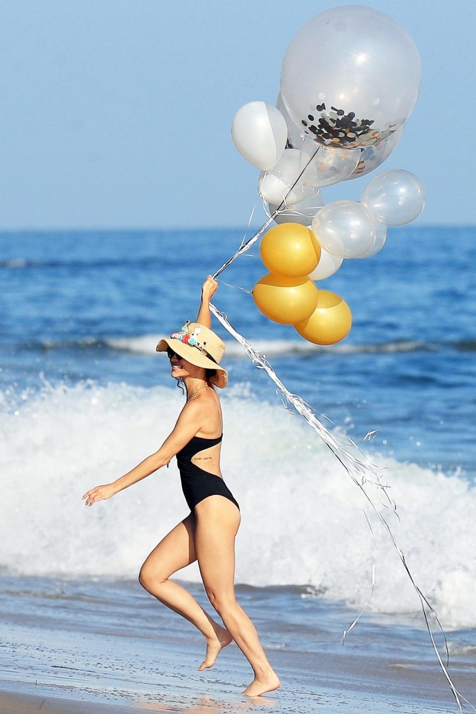 <p>Cara Santana carries a handful of balloons while celebrating her birthday with friends at the beach in Malibu on Saturday. </p>