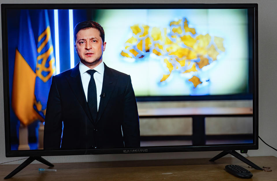 A television screen shows Ukrainian President Volodymyr Zelensky giving an address.