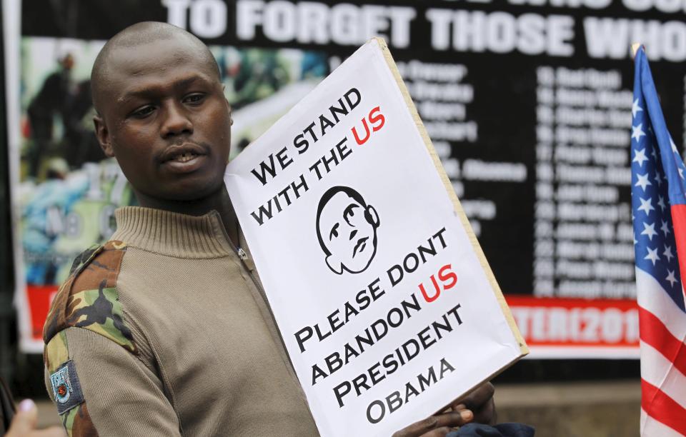 A survivor of the August 1998 U.S. embassy bombing holds a placard as he protests outside the memorial park ahead of a scheduled state visit by U.S. President Obama, in Kenya's capital Nairobi