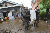 Army soldiers carry debris from a damaged house following flooding from heavy rains in Cheorwon, South Korea, Thursday, Aug. 6, 2020. Torrential rains continuously pounded South Korea on Thursday, prompting authorities to close parts of highways and issue a rare flood alert near a key river bridge in Seoul. (AP Photo/Ahn Young-joon)