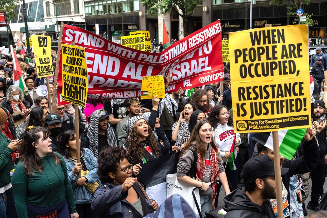 Marchers holding pro-Palestinian signs on a city street. 