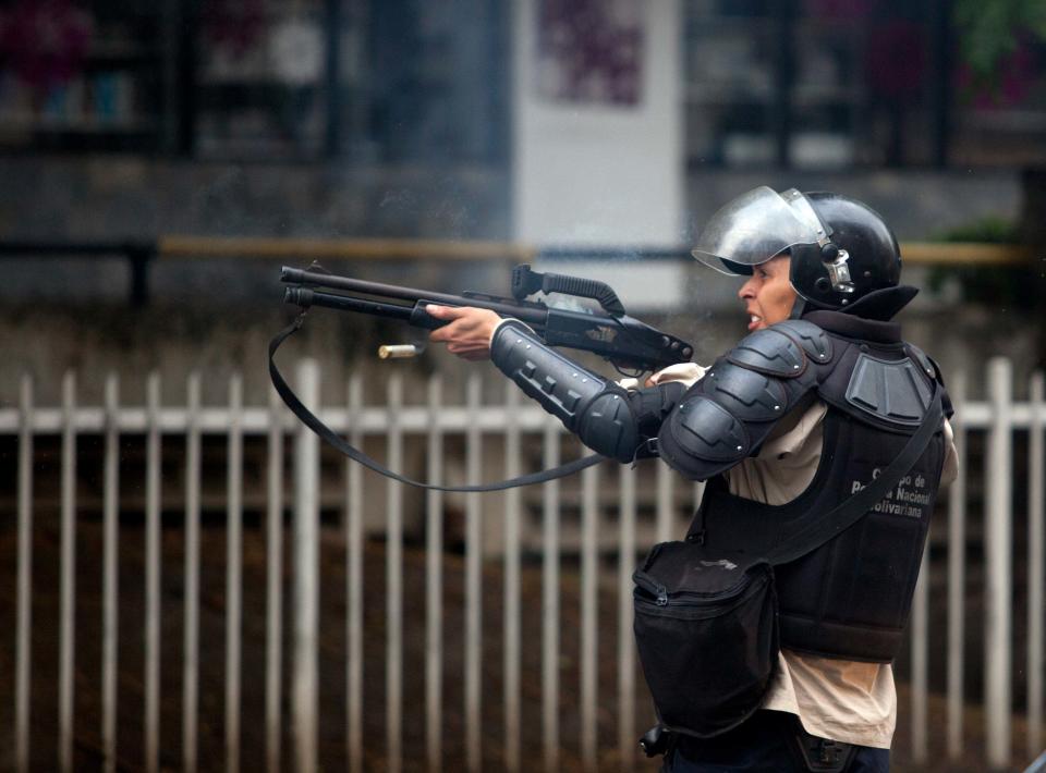 A Bolivarian National Police officer fires rubber bullets at demonstrators after clashes broke out at an at anti-government protest in Caracas, Venezuela, Thursday, May 8, 2014. Demonstrators took to the streets after a pre-dawn raid by security forces that broke up four camps maintained by student protesters and arrested more than 200 people. The tent cities were installed more than a month ago in front of the offices of the United Nations and in better-off neighborhoods in the capital to protest against President Nicolas Maduro's socialist government. (AP Photo/Alejandro Cegarra)