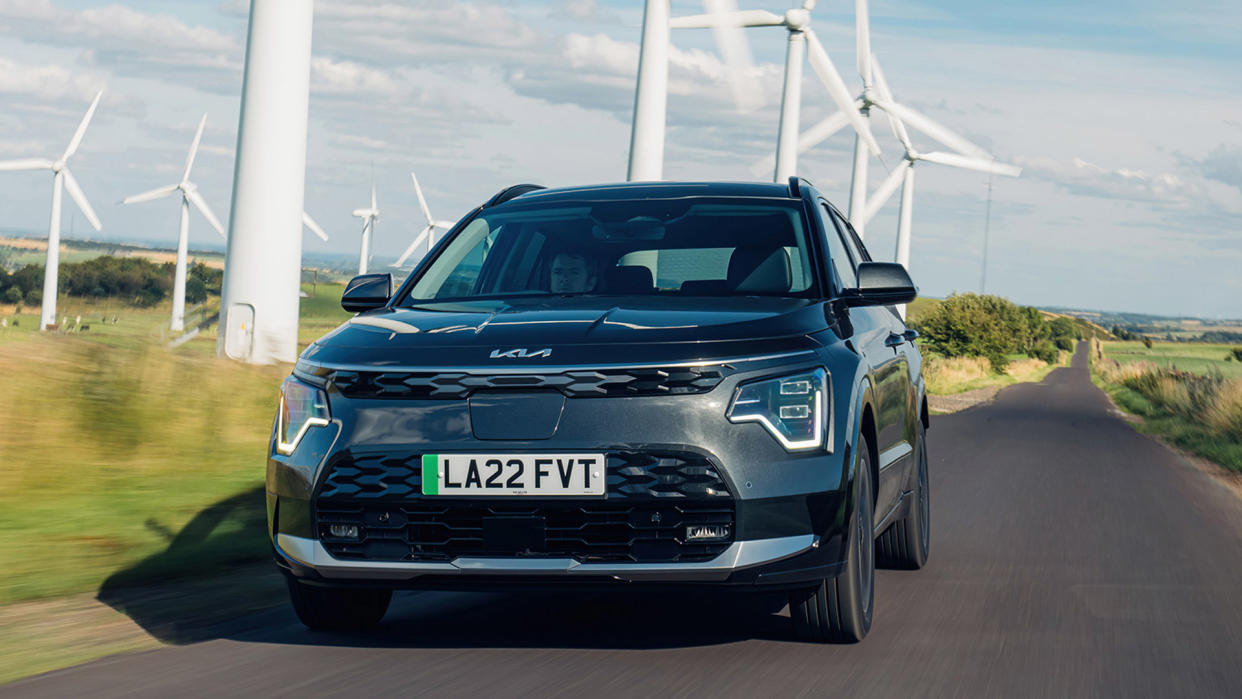  Kia e-Niro in black driving in front of wind turbines 