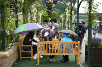 Spectators shelter under umbrellas during a rain delay on day one of the Wimbledon Tennis Championships in London, Monday June 28, 2021. (AP Photo/Alberto Pezzali)