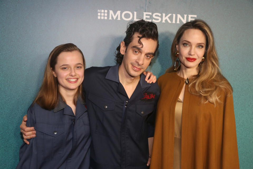 Vivienne Jolie, a gentleman, and Angelina Jolie at a Moleskine event, posing together in casual and stylish attire