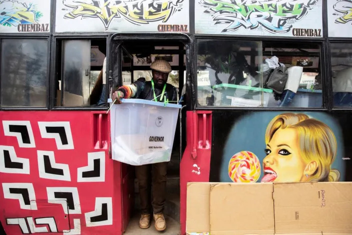 Man coming off a bus with art on it. He is carrying a large box.