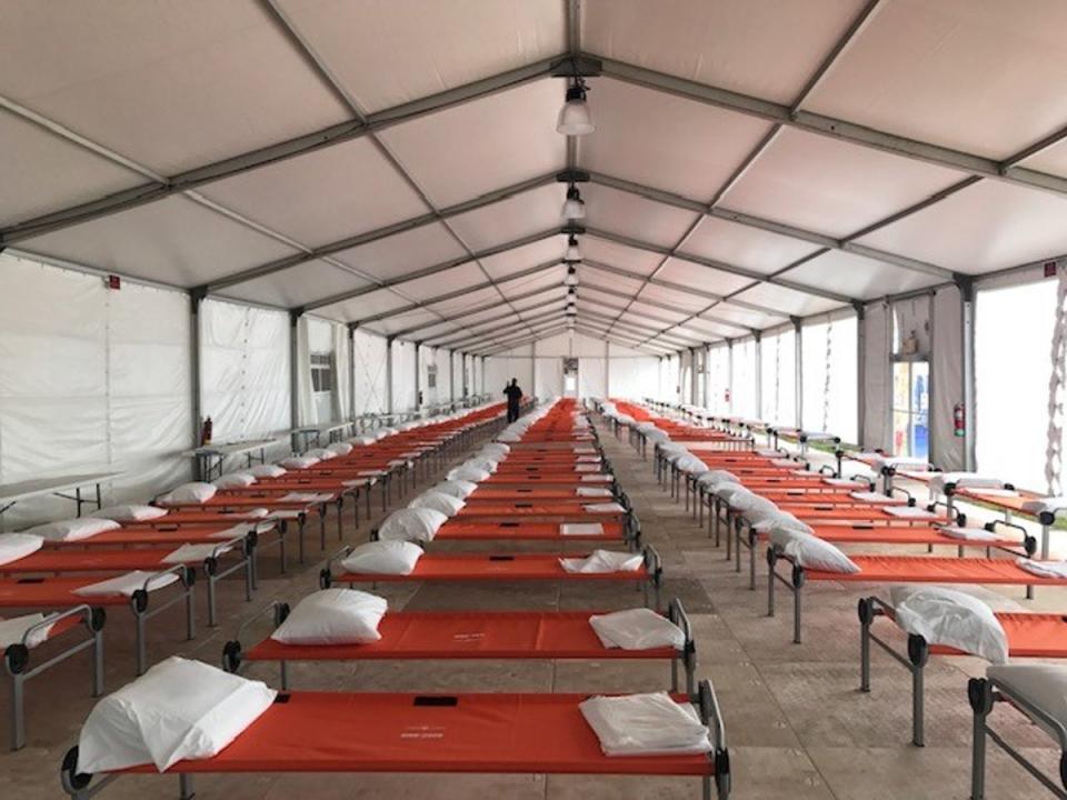 A model of a shelter in The Bronx for newly arrived migrants shows rows of cots under a large tent-like facility. (City of New York)