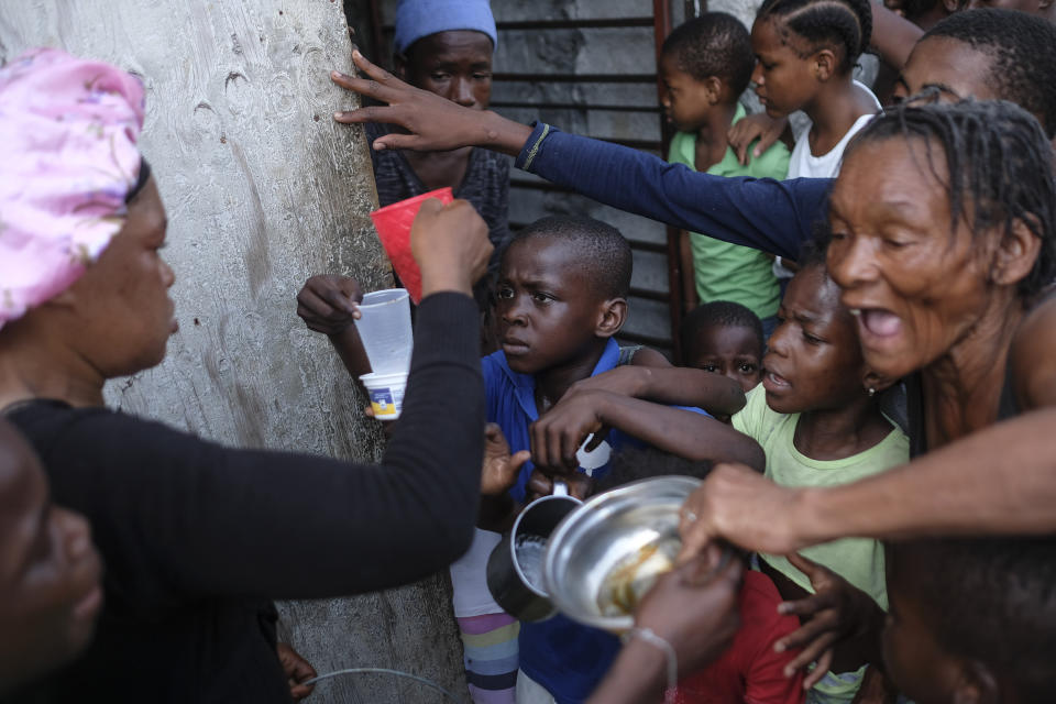 FILE - A woman gives out coffee to people living at a shelter for families displaced by gang violence, in Port-au-Prince, Haiti, Nov. 13, 2021. Few places in the world are so dependent on aid groups as Haiti, a nation frequently called "the republic of NGOs." (AP Photo/Matias Delacroix, File)