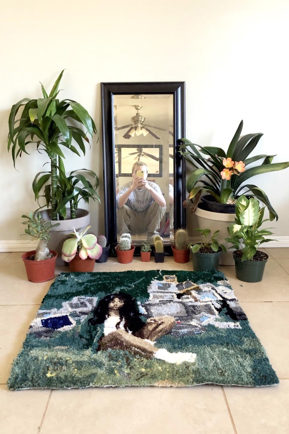 Oscar Morales, reflected in a mirror, with the rug he made based on SZA's "Ctrl" album cover.