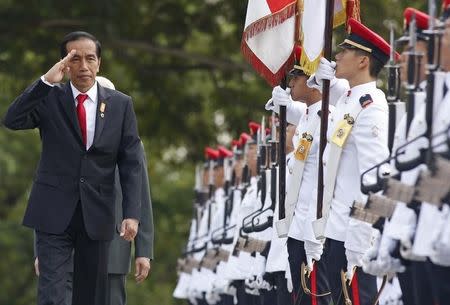 Indonesian President Joko Widodo salutes as he inspects an honour guard with his Singaporean counterpart Tony Tan (behind) during a welcome ceremony at the Istana in Singapore July 28, 2015. REUTERS/Edgar Su