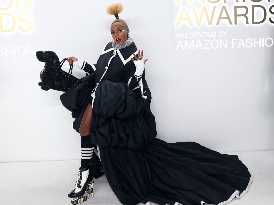 Janelle Monáe in black dress with black dog bag in front of white background