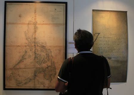 A local photographer looks at an ancient map on display at a Catholic university in Manila September 11, 2014. REUTERS/Romeo Ranoco