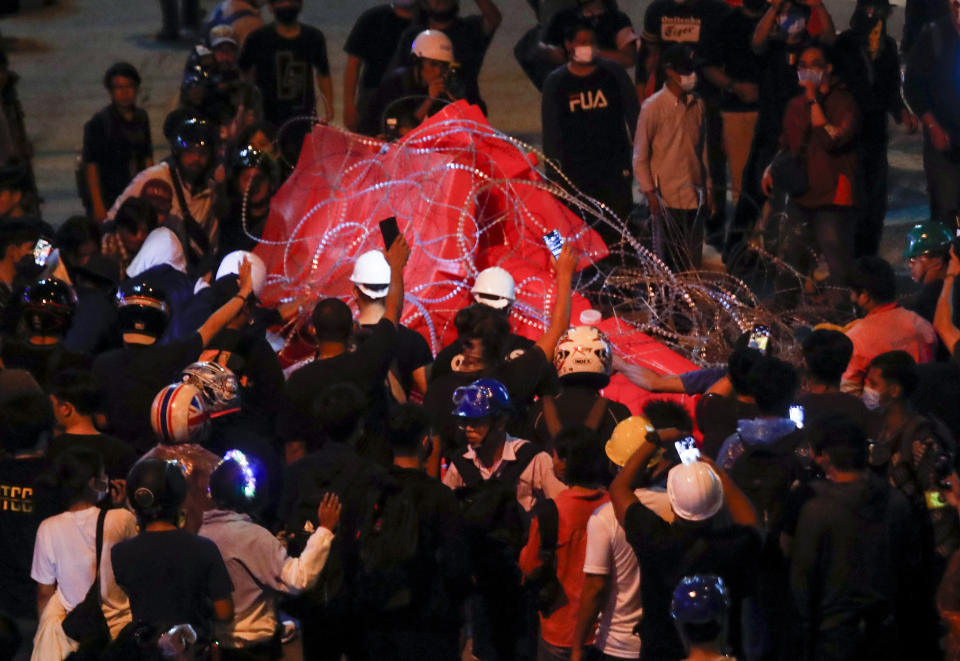 Pro-democracy activists remove barbed wires and barricades during their march to the Government House, prime minister's office during a protest march in Bangkok, Thailand, Wednesday, Oct. 21, 2020. Thailand's prime minister on Wednesday pleaded with his countrymen to resolve their political differences through Parliament, as student-led protests seeking to bring his government down continued for an eighth straight day. (AP Photo/Sakchai Lalit)