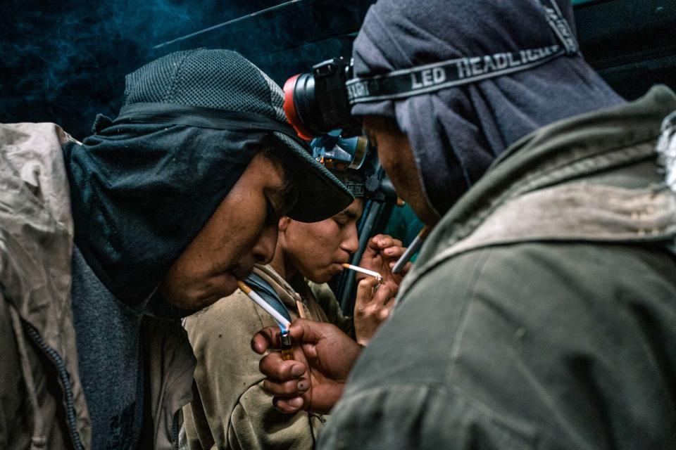 Men lean in to get a light for their cigarettes.