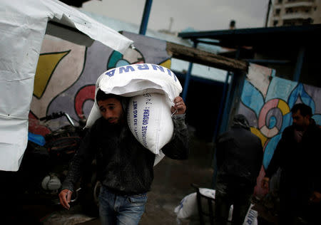 A Palestinian man carries sacks of flour outside a United Nations food distribution center in Al-Shati refugee camp in Gaza City January 17, 2018. REUTERS/Mohammed Salem
