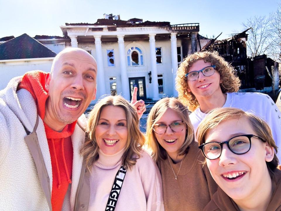 Mike Thakur, left, poses with his wife and three children in front of a Franklin mansion that was heavily damaged in a 2022 fire. Thakur put in an offer for the mansion Jan. 20, 2023, and is now under contract.