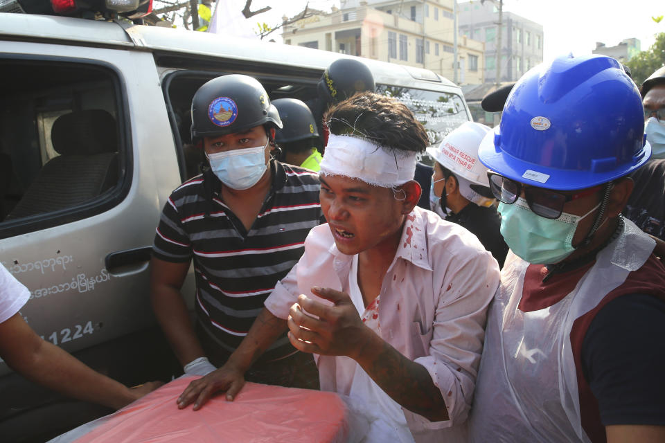 In this Feb. 26, 2021, file photo, an injured protester is escorted as police tried to disperse a demonstration against the military coup in Mandalay, Myanmar. Myanmar's security forces have killed scores of demonstrators protesting a coup. The outside world has responded so far with tough words, a smattering of sanctions and little else. (AP Photo)