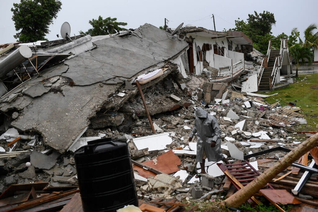 A man walks on the rubble of a collapsed hotel the morning after Tropical Storm Grace swept over Port Salut, Haiti, Tuesday, Aug. 17, 2021, three days after a 7.2 magnitude quake. (AP Photo/Matias Delacroix)
