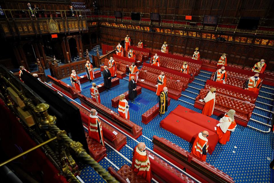 Members of the House of Lords wearing face coverings, stand socially distanced as they await the arrival of Britain's Queen Elizabeth II during the State Opening of Parliament at the Houses of Parliament in London on May 11, 2021, which is taking place with a reduced capacity due to Covid-19 restrictions. - The State Opening of Parliament is where Queen Elizabeth II performs her ceremonial duty of informing parliament about the government's agenda for the coming year in a Queen's Speech. (Photo by Aaron Chown / POOL / AFP) (Photo by AARON CHOWN/POOL/AFP via Getty Images)