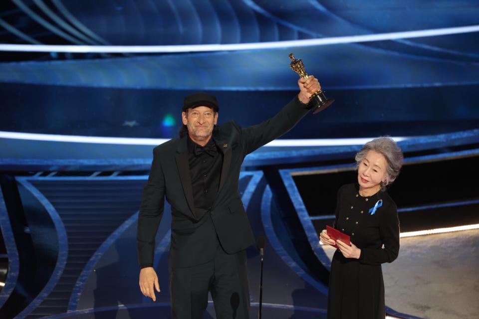 Troy Kotsur accepts the Actor in a Supporting Role award for 'CODA' from Yuh-jung Youn at the 94th Academy Awards.