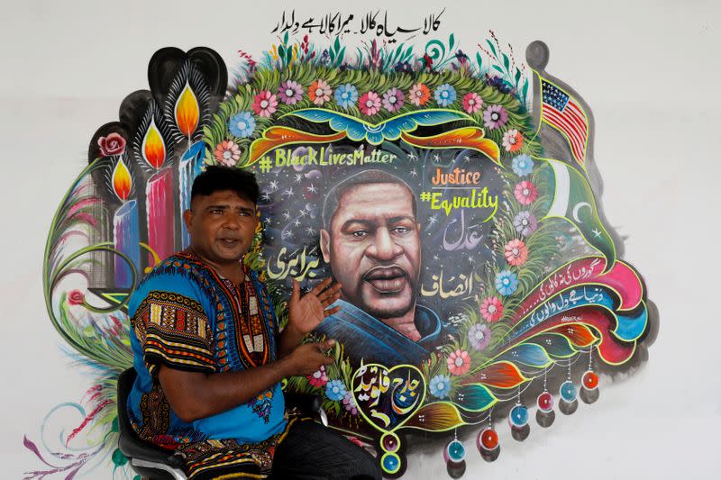 FILE PHOTO: FILE PHOTO: Pakistani truck-art painter Haider Ali, 40, gestures as he speaks with Reuters next to a mural he painted, depicting George Floyd, who died in Minneapolis police custody in U.S., in Karachi