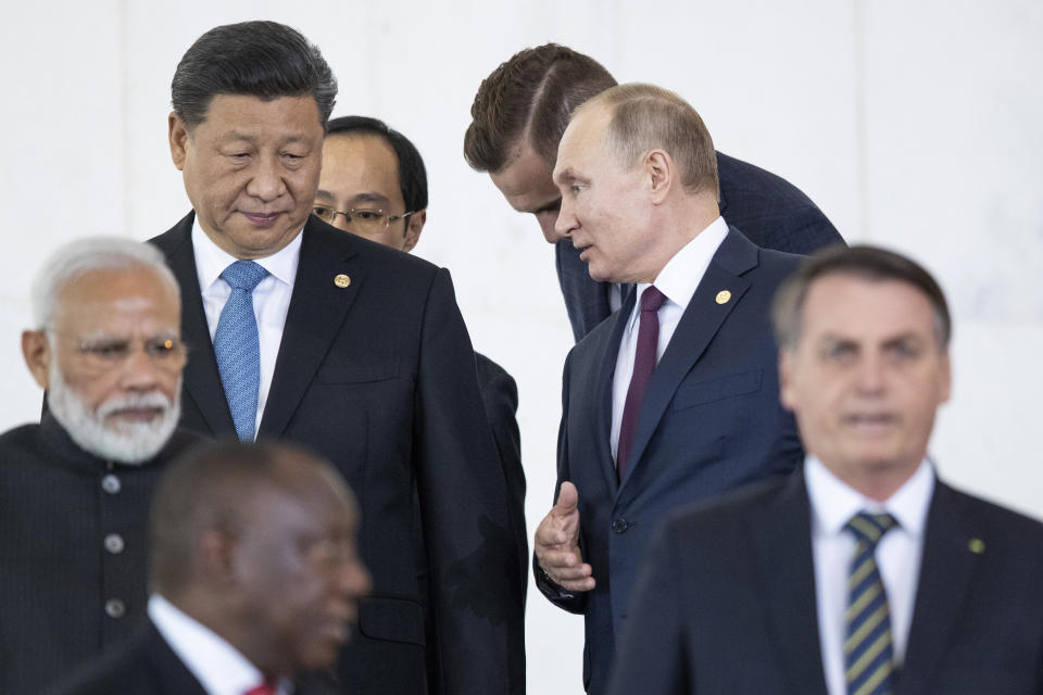 Russian President Vladimir Putin, top right, and China's President Xi Jinping, top left, talk to each other as they and other leaders walk to attend the BRICS emerging economies at the Itamaraty palace in Brasilia, Brazil, Thursday, Nov. 14, 2019. (AP Photo/Pavel Golovkin, Pool)