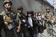 Lebanese teachers react to the sounds from nearby armed clashes as they flee their school under the protection of Lebanese soldiers after a clashes erupted along a former 1975-90 civil war front-line between Muslim Shiite and Christian areas at Ain el-Remaneh neighborhood, in Beirut, Lebanon, Thursday, Oct. 14, 2021. Armed clashes broke out in Beirut Thursday during the protest against the lead judge investigating last year's massive blast in the city's port, as tensions over the domestic probe boiled over. (AP Photo/Hussein Malla)