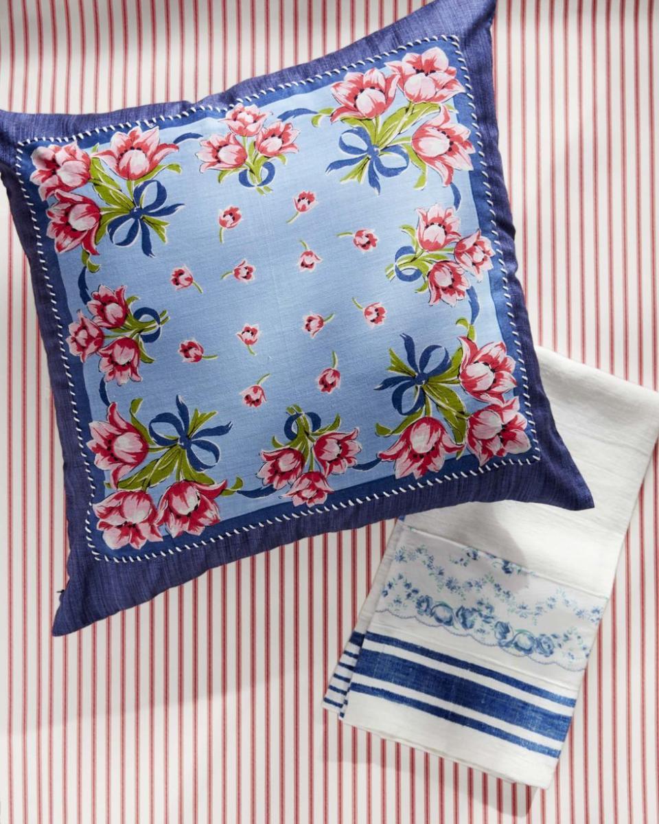 navy throw pillow with a blue, pink, and green floral handkerchief whipstiched to the front, beside a blue and white tea towel also embellished with a handkerchief