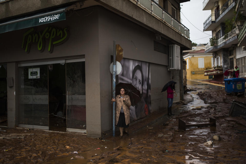 <p>Women holding umbrellas stand next to a damaged shop, in a flooded street of Mandra, northwest of Athens, on Nov. 15, 2017, after heavy overnight rainfall. (Photo: Angelos Tzortzinis/AFP/Getty Images) </p>