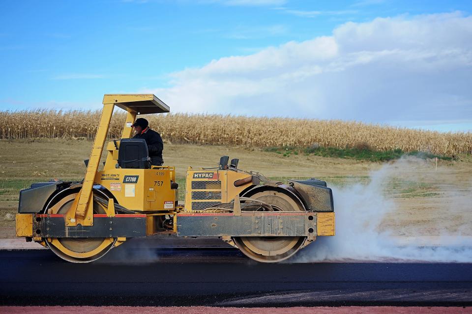 Ryan McKnelly, with Myrl & Roy's Paving, uses a steel roller while paving a street in eastern Sioux Falls, S.D.