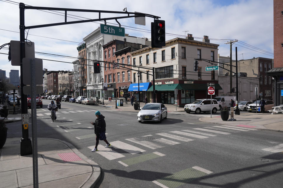 Pedestrians cross the street at the intersection of Washington and 5th in Hoboken, N.J., Thursday, Feb. 22, 2024. This intersection has curb extenders, which bumps out the sidewalk near crosswalks, preventing parking near the intersection and increasing visibility for pedestrians. (AP Photo/Seth Wenig)