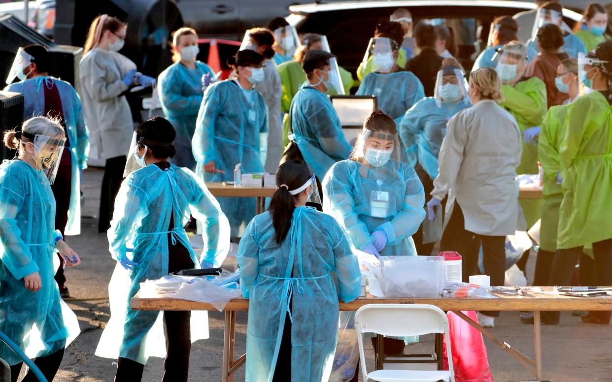 Medical personnel prepare to test hundreds of people lined up in vehicles in Phoenix's western neighbourhood of Maryvale - AP