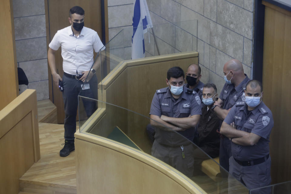 Yakub Kadari is surrounded by guards in a courtroom in Nazareth, Israel, after he and three other Palestinian fugitives were captured on Saturday, Sept. 11, 2021. Israeli police on Saturday said they have arrested four of the six Palestinians who broke out of a maximum-security prison this week — including a famed militant leader whose exploits over the years have made him a well-known figure in Israel. (AP Photo/Sebastian Scheiner)