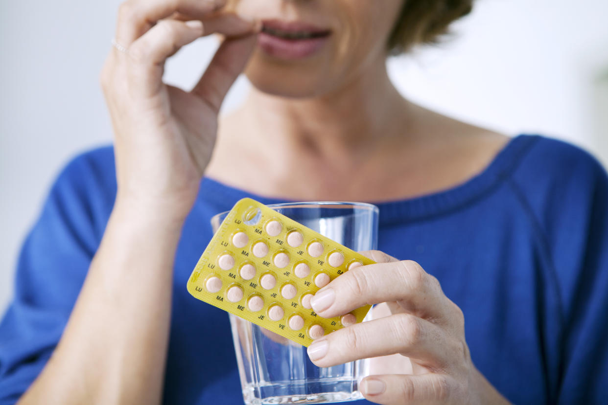 A woman holding a package of pills.