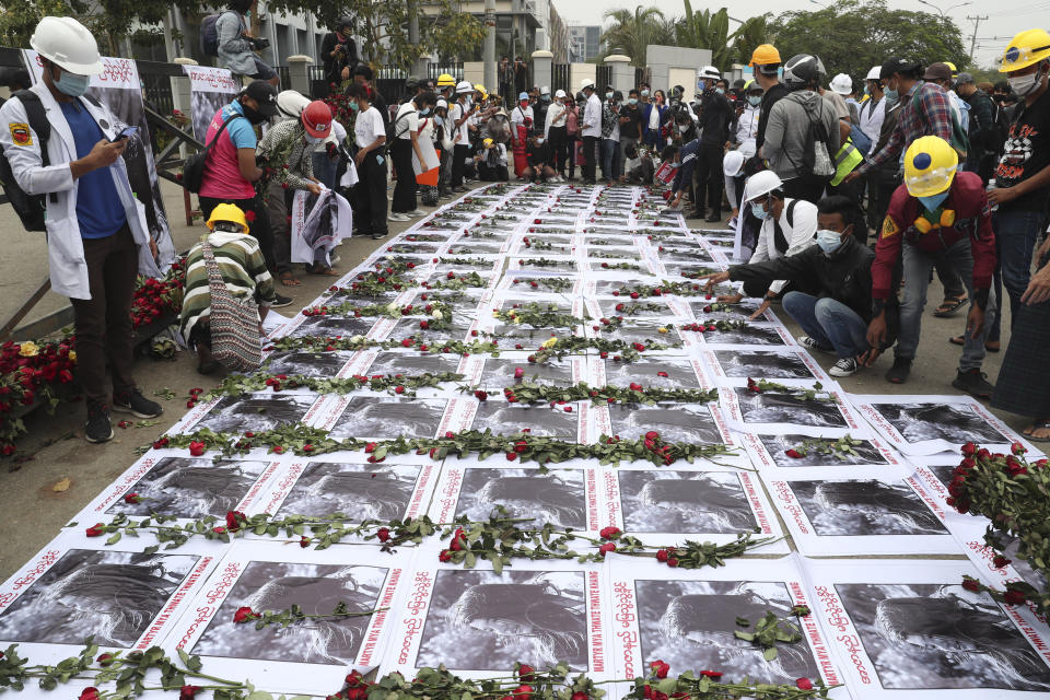 People surround rows of images of Mya Thwet Thwet Khine adorned with flowers on a roadside in Mandalay, Myanmar Saturday, Feb. 20, 2021. Anti-coup protesters in Myanmar's two largest cities on Saturday paid tribute to the young woman who died a day earlier after being shot by police during a rally against the military takeover. (AP Photo)