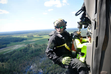 Waterway Conservation Officer Anthony Beers, with the Pennsylvania Helicopter Aquatic Rescue Team, prepares to conduct an aerial rescue on a hoist from a Pennsylvania National Guard Black Hawk helicopter in Nichols, South Carolina, September 19, 2018. Capt. Travis Mueller/U.S. Army/Handout via REUTERS
