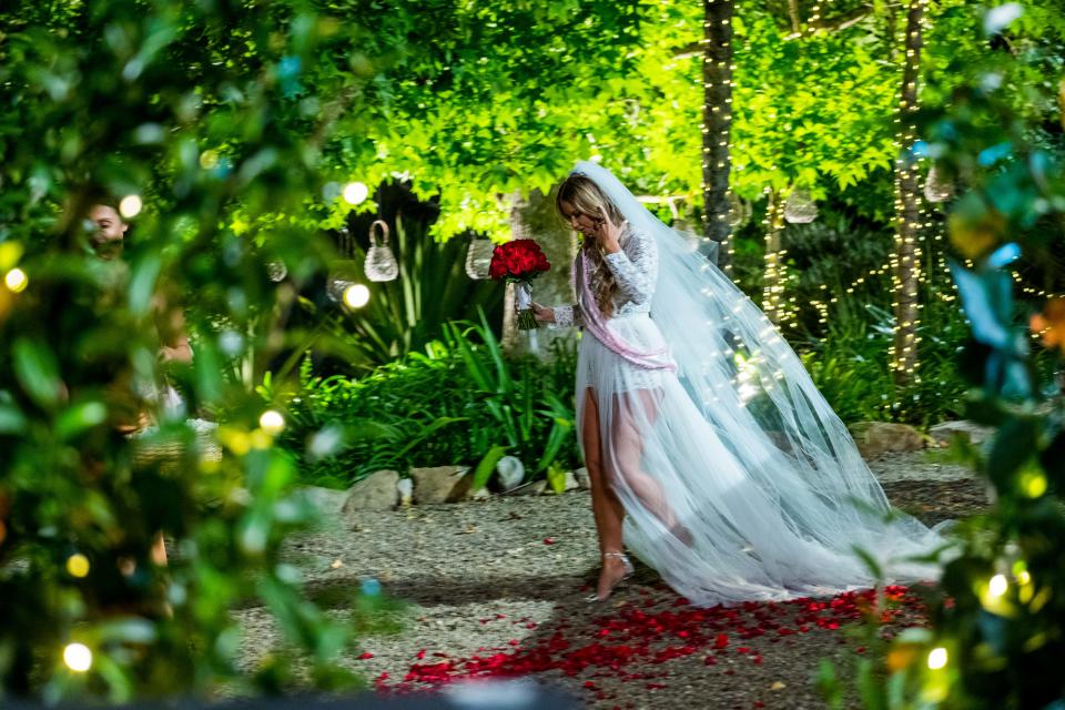 Bachelor Australia contestant in wedding dress with bridesmaid and bouquet of roses