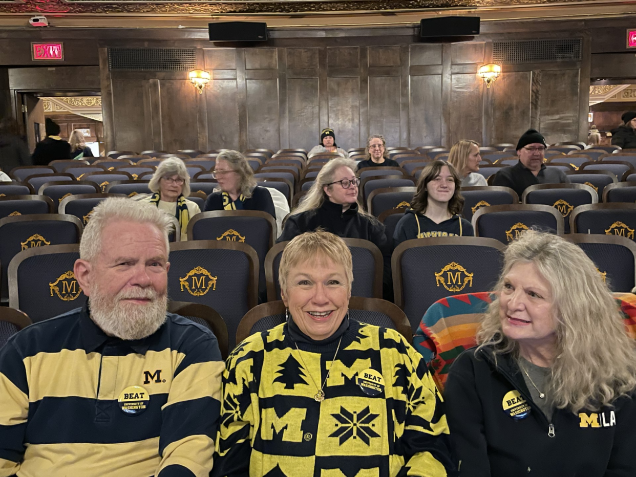 Jeanie Mack-Powers, center, a retired nurse from Ann Arbor, sits with family and friends in the city’s Michigan Theater ready to watch the simulcast of her Michigan Wolverines compete in the College Football Playoff national championship game on Monday, Jan. 8, 2024.
