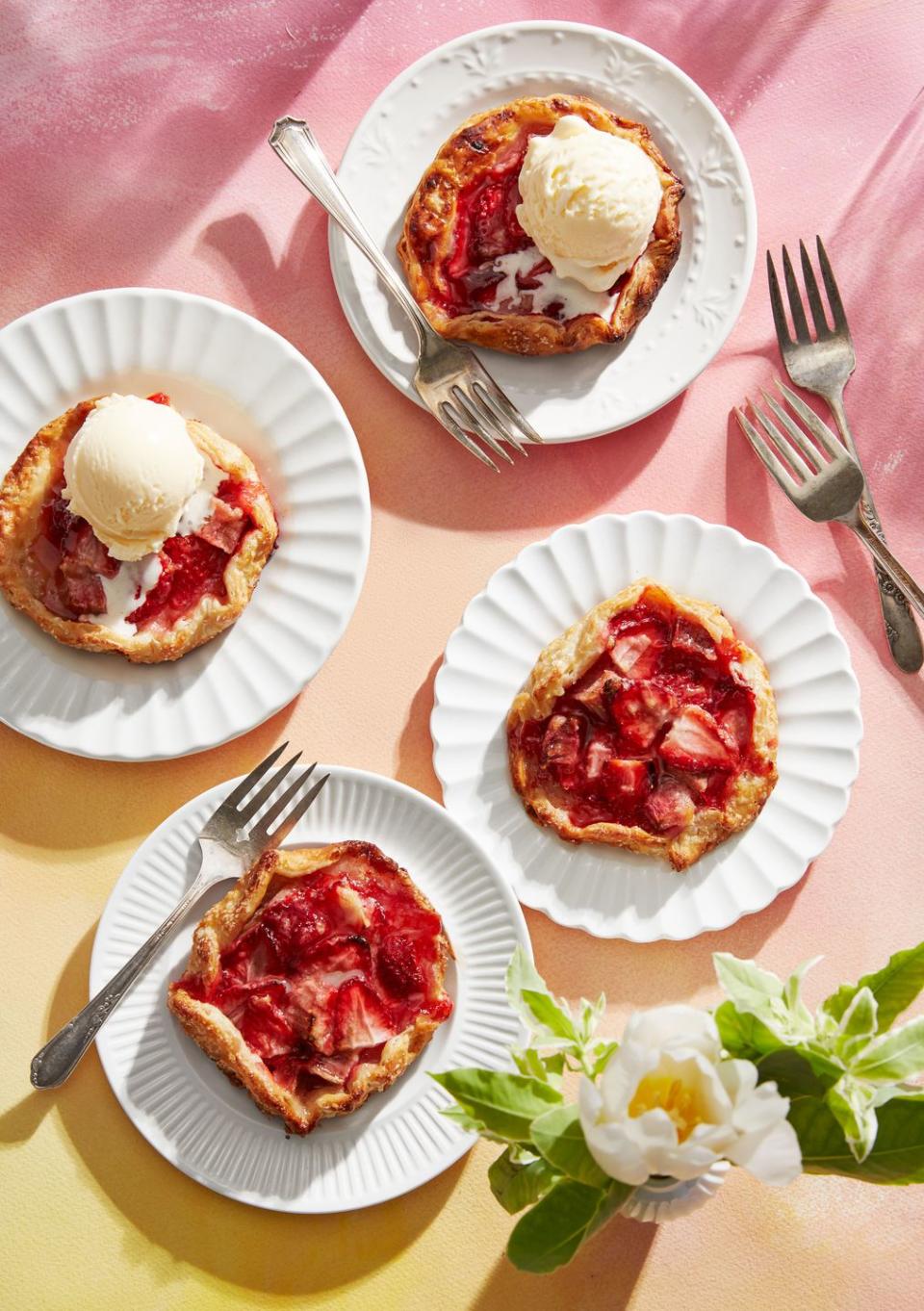 4 mini strawberry rhubarb galettes on individual plates with ice cream