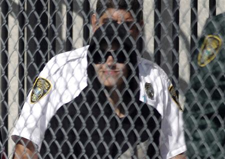 Teen pop star Justin Bieber, in a black hooded sweatshirt, departs a Miami-Dade County jail in Miami, Florida January 23, 2014. REUTERS/Andrew Innerarity