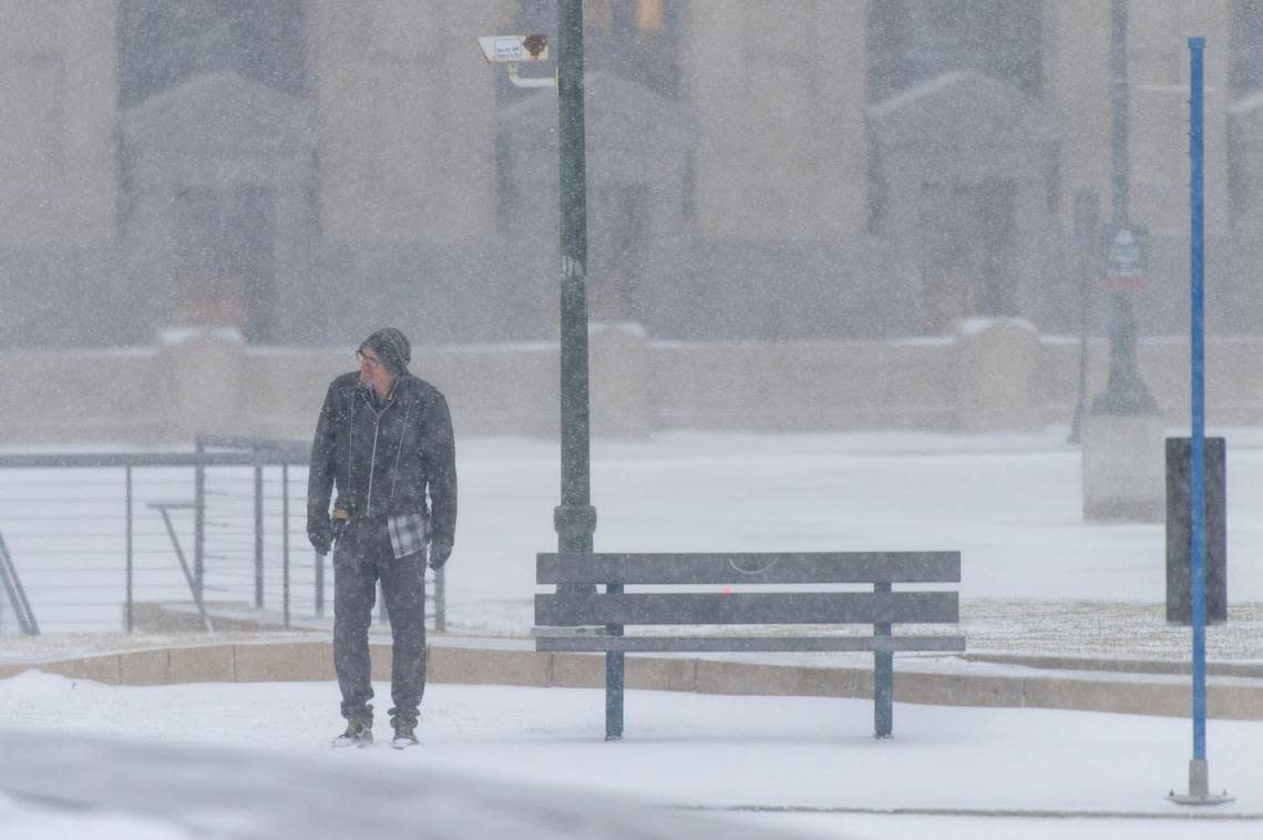 A man waits for a city bus as snow falls outside of Union Station on Thursday, Dec. 22, 2022, in Kansas City.
