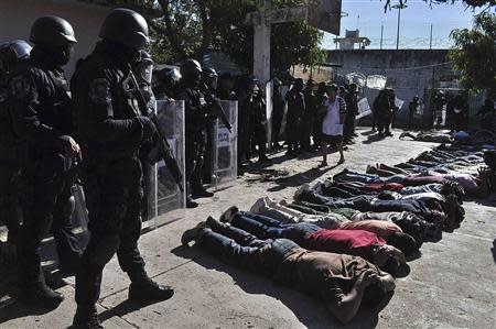 Inmates lie on the ground as riot policemen keep watch during an operation after a gunfight at the Tuxpan prison in Iguala, in the Mexican State of Guerrero January 3, 2014. REUTERS/Jesus Solano