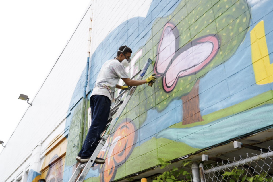 Multimedia artist Ernesto Gomez of Racine works with the TRUE Skool organization to paint a mural inspired by the Emmy-nominated documentary "When Claude Got Shot" on Friday in Milwaukee.