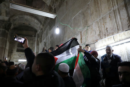Palestinian Muslims hold a Palestinian flag as they attend Friday prayers inside the Golden Gate near Al-Aqsa mosque in Jerusalem's Old City February 22, 2019. REUTERS/Ammar Awad
