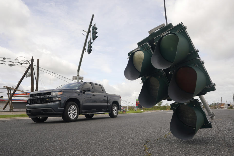 Traffic passes by a traffic light hanging from a cable after Hurricane Ida moved through Monday, Aug. 30, 2021, in LaPlace, La. (AP Photo/Steve Helber)