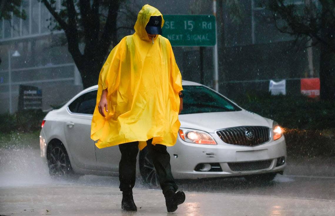 A poncho-wearing pedestrian smokes in the rain as he walks along the sidewalk off Brickell Avenue in Miami, Florida, on Tuesday, September 27, 2022. All of South Florida is now in alert for Hurricane Ian’s tropical storm-force winds.