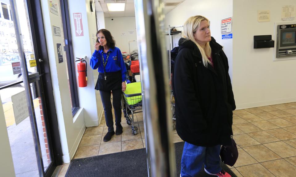 Pat O'Niell, a laundry attendant at Canal Laundry, a laundromat down the street from Robert Morris Apartments, looks out the window at the crime scene while customer Jamie Eatoa, waits for laundry to dry.