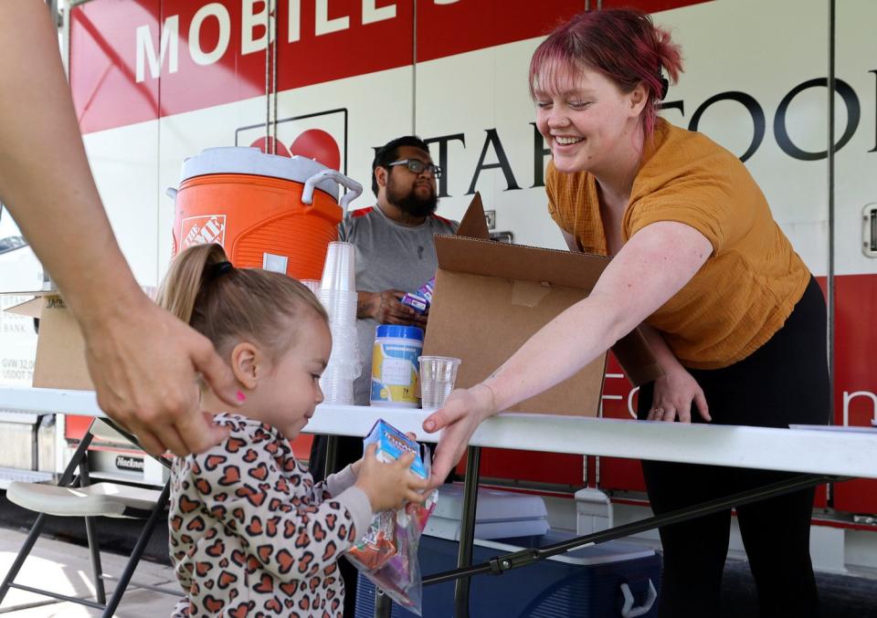 Isabella Reynolds, Utah Food Bank's mobile school pantry coordinator, hands a bag of food to Navie Hancock as part of the USDA’s Summer Food Service Program at Downtown Park in Pleasant Grove on Wednesday. The Utah Food Bank gave out 140 meals at Downtown Park before moving to another location.